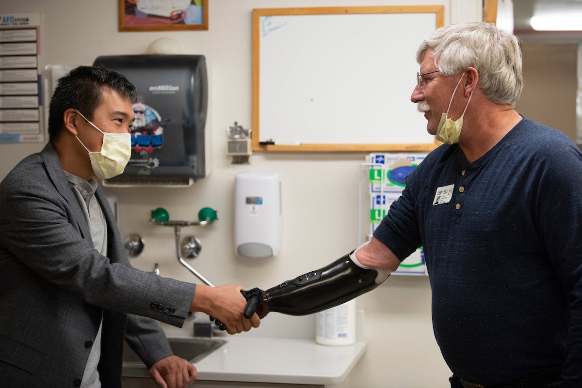 Surgeon Andrew Li shakes the prosthetic hand of former patient David Brockman, a retired fire captain, who had targeted muscle re-innervation surgery on his amputated hand. (Greg Urquiaga/˽̳ Davis)