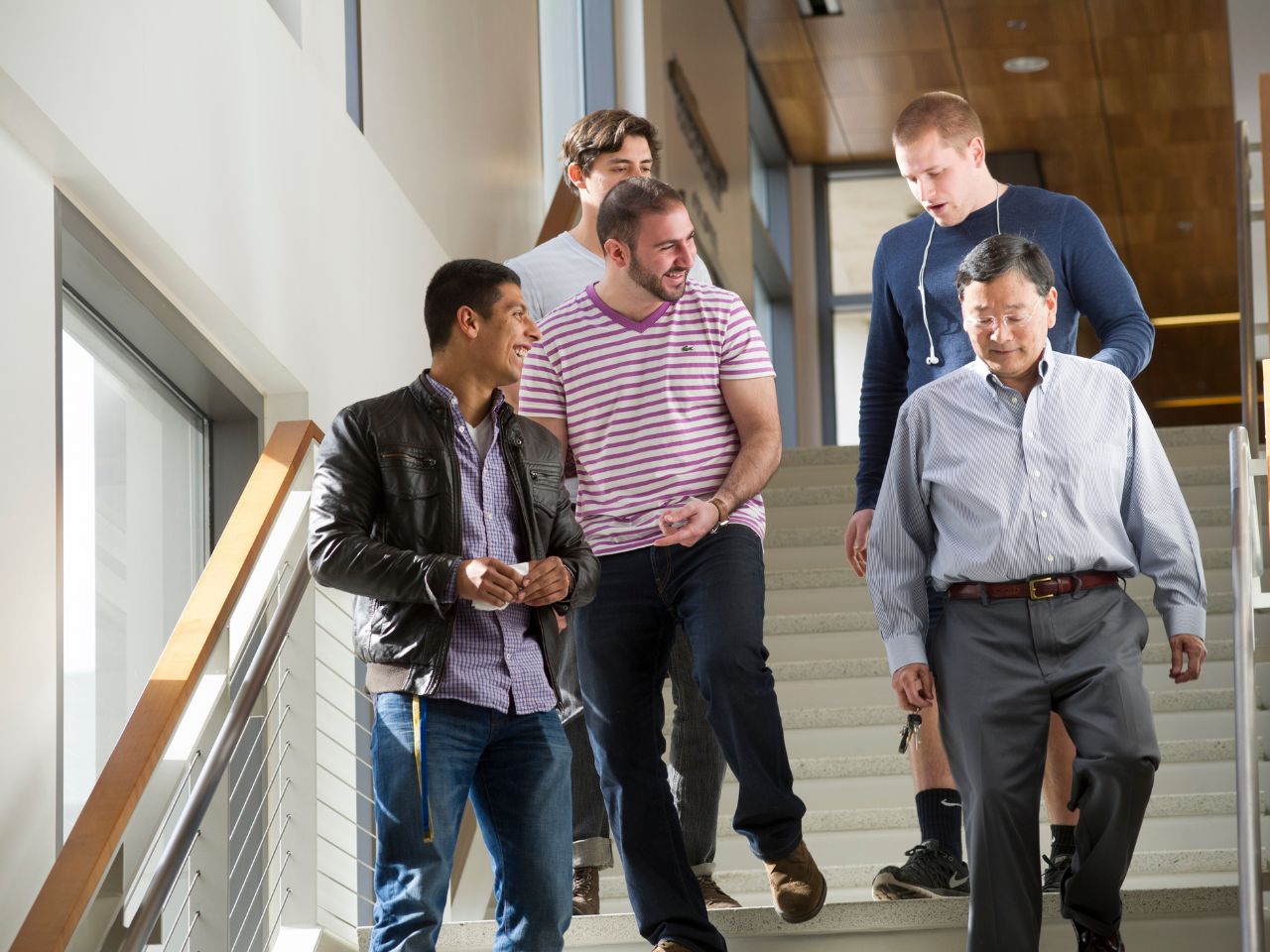 A group of four students and ˽̳ Davis School of Law Professor Clay Tanaka laugh and converse while descending the stairs in King Hall.
