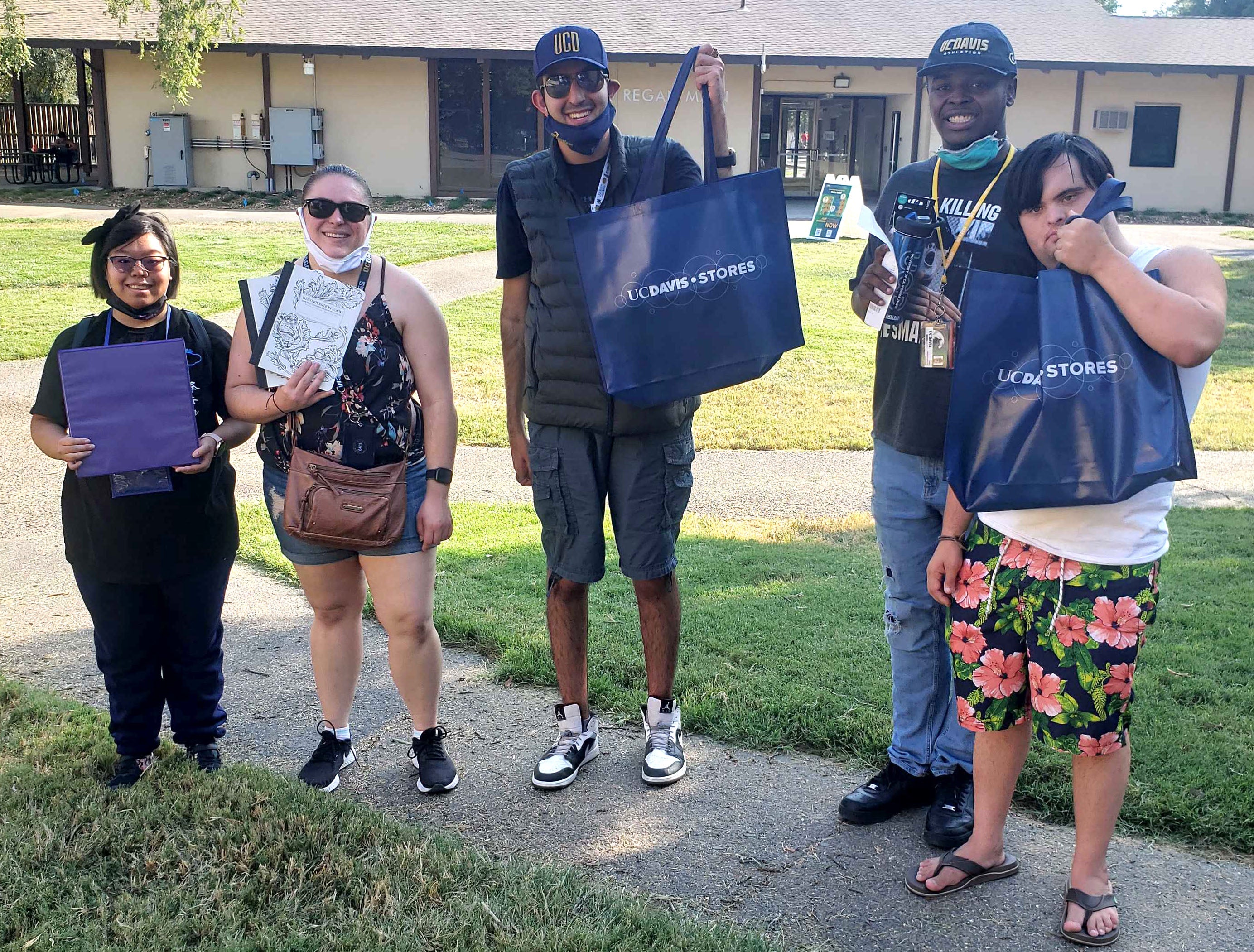 Five students stand on a sidewalk holding ˽̳ Davis bags