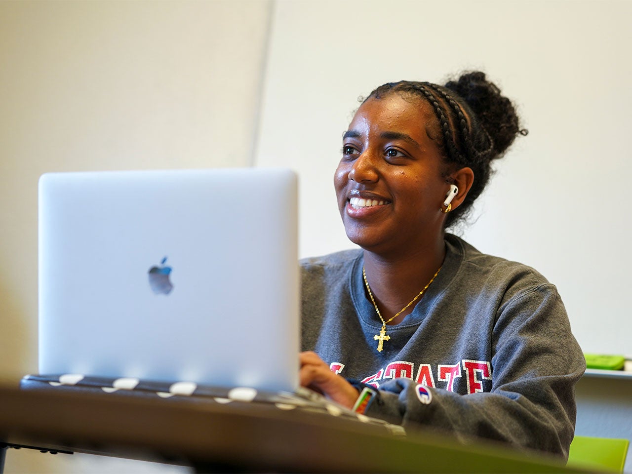 A ˽̳ Davis student smiles while typing on a silver laptop.