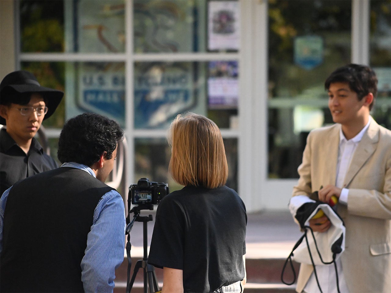 Three ˽̳ Davis students review footage while an actor waits for instruction.