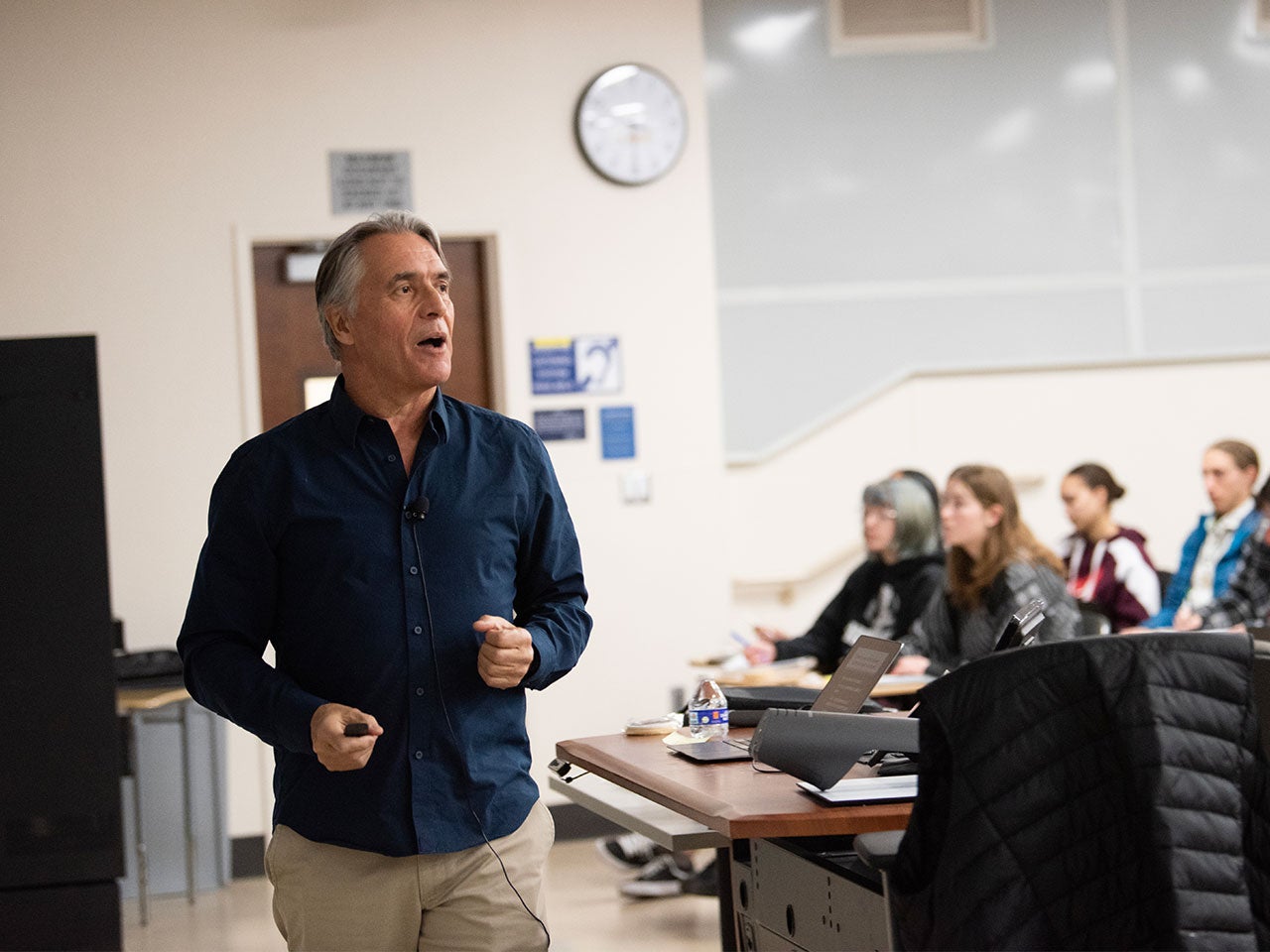 A ˽̳ Davis professor in a dark blue button-up shirt teaches a class.