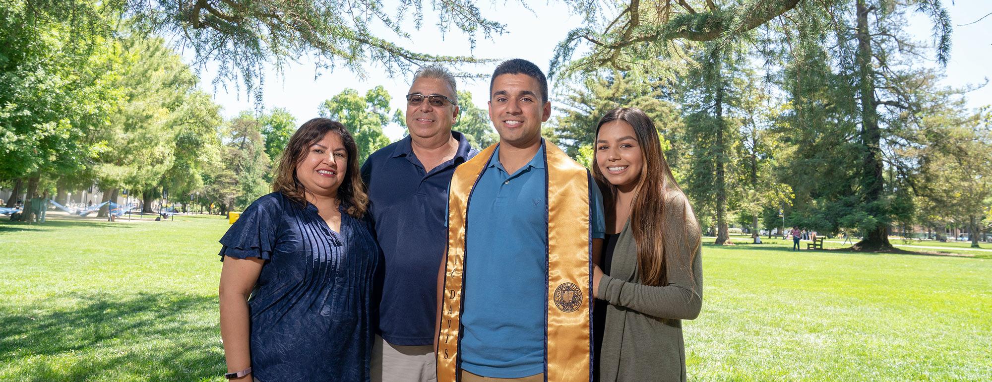 Parents pose with their ˽̳ Davis graduate son on the quad 