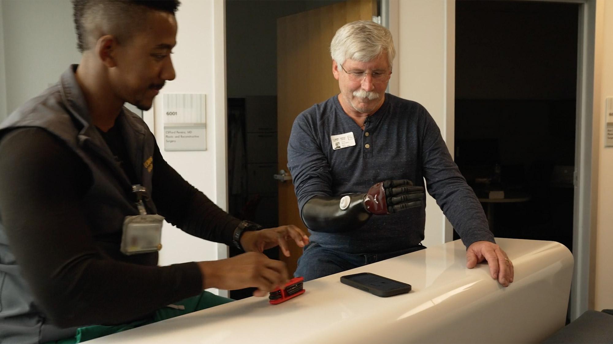 David Brockman, a retired CalFire captain, and ˽̳ Davis Health certified prosthetist orthotist Laduan Smedley test out prosthetic arm