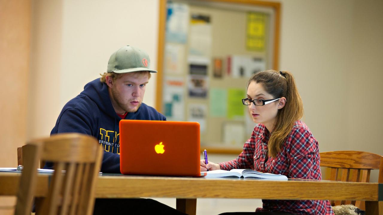 Two students work in front of a laptop at ˽̳ Davis.
