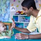 Neeraj Senthil and a toddler share a high 5 in a playroom at ˽̳ Davis Children's Hospital.