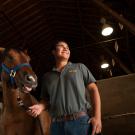 A student smiles with a horse in a barn at ˽̳ Davis. 