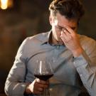 Man rubbing his forehead while drinking red wine. ˽̳ Davis scientists theorize that a flavanol found naturally in red wine can interfere with the metabolism of alcohol and cause "red wine headache."