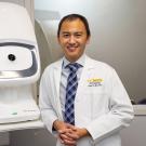 Glenn Yiu, in white lab coat, with ophthalmology equipment, ˽̳ Davis Health