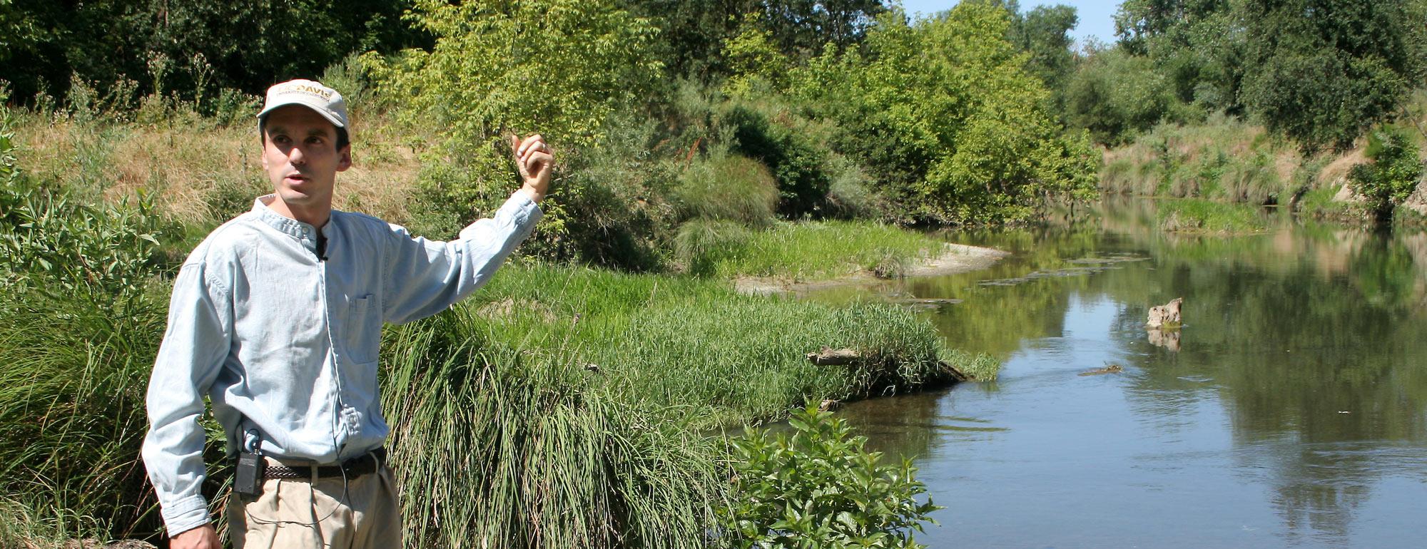 A ˽̳ Davis researcher points at a wetlands areas behind him